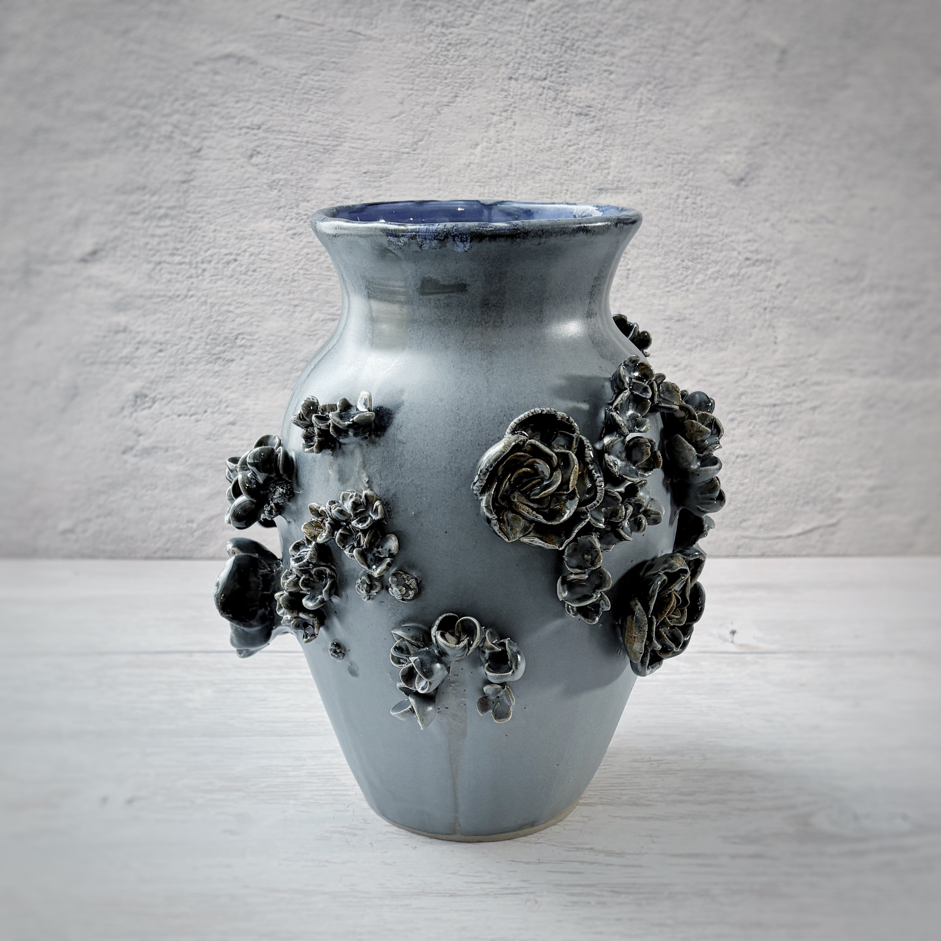 Jarrón con aplicacioenes de flores  en azul.